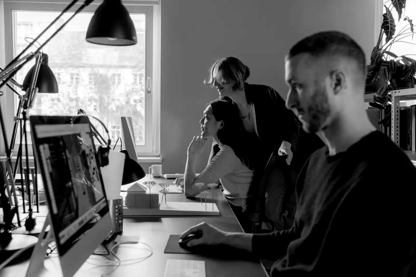 Three colleagues reviewing work together at a studio desk.